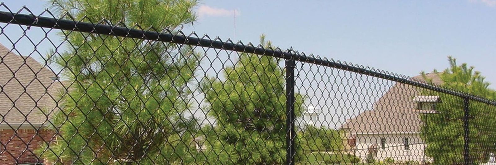 Black vinyl-coated chain link fence with top rail running along a residential backyard