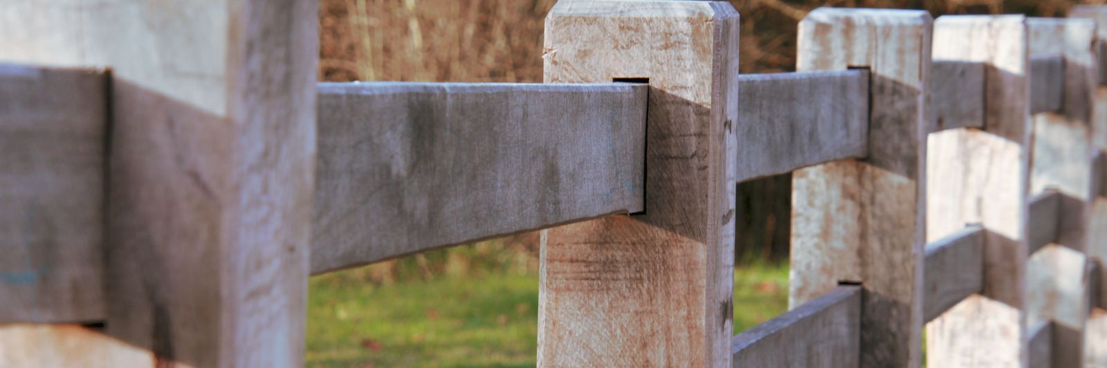Wooden post and rail ranch fence in front of dry brush